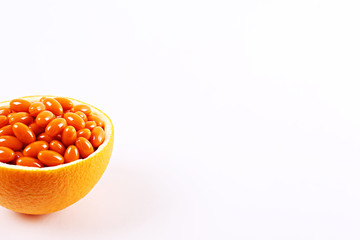 Conceptual image of vitamin c capsules in container made of orange peel. Halved citrus fruit cleaned from pulp core and filled with colorful pills. Background, copy space, close up.