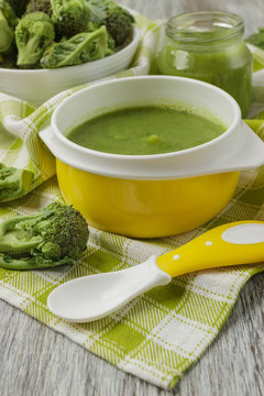 Fresh broccoli in the bowl, and portion of puree made from crushed broccoli, blurred background