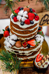Wedding cake with fruit and an old wooden table with needles of cones and leaves during a wedding ceremony in winter on snow in the middle of a forest covered with fresh snow