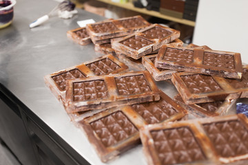 production and cooking concept - close up of chocolate cream in candy molds at confectionery shop