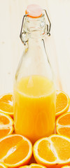 Bottle of freshly pressed orange juice with sliced orange halfs