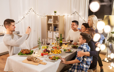 celebration, holidays and people concept - happy family having dinner party at home and taking selfie by smartphone