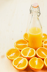Bottle of freshly pressed orange juice with sliced orange halfs