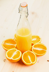 Bottle of freshly pressed orange juice with sliced orange halfs