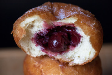 Donuti with cherries on black background. Close-up