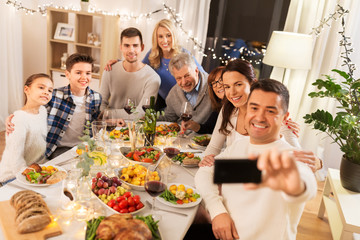 celebration, holidays and people concept - happy family having dinner party at home and taking selfie by smartphone