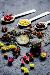 Spoons with herbs on dark stone background
