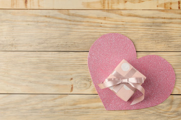 Pink gift box and a heart on a natural wooden background. Valentine's Day. top view with space for text
