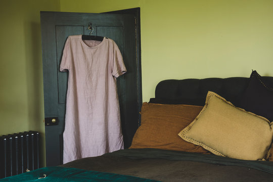 Interior View Of Bedroom With Light Green Walls, Double Bed With And Pale Pink Linen Nightgown On Hanger Over Door.