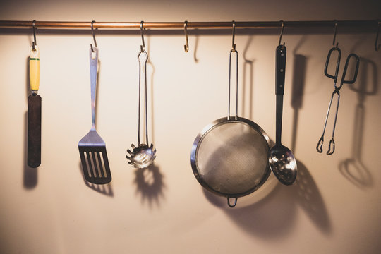 Close up of kitchen utensils suspended from copper pipe.