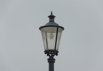 Fototapeta na wymiar Metallic black street lamp on a gray background on a cloudy day