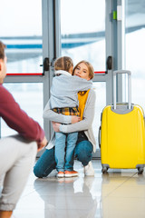 Fototapeta na wymiar mother hugging daughter near luggage in airport