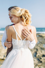 Fototapeta na wymiar Wedding photo shoot on the beach. Couple at sunset walks and hugs, laughs and kisses.