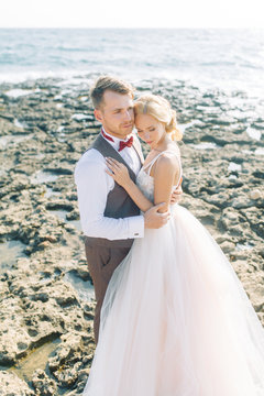 Wedding photo shoot on the beach. Couple at sunset walks and hugs, laughs and kisses.