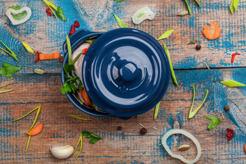 Raw chicken in a pot with vegetables on old wooden table