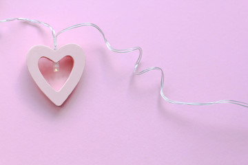 Heart shape made of wood, pink background.