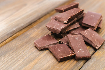 Dark chocolate is lying on a wooden background. Soft focus