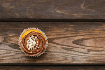 Chocolate muffin sprinkled with nut crumbs on a wooden background. Top view