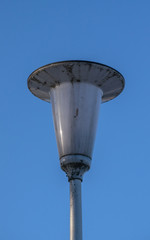 Dirty street lamp against the blue sky in the afternoon