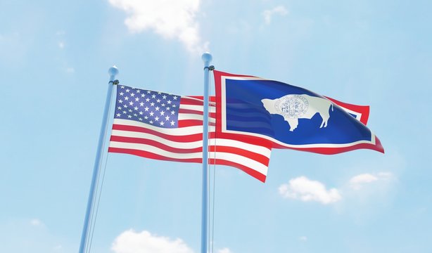 USA and state Wyoming, two flags waving against blue sky. 3d image