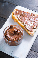 hazelnut cream sandwich breakfast and ingredients on white cutting board, black wooden table background