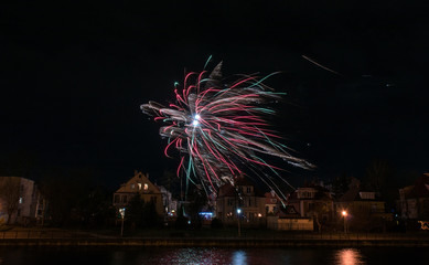 Разноцветный салют в ночном небе на берегу озера