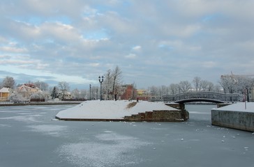 Winter landscape on the lake shore on a sunny day with snow and blue sky