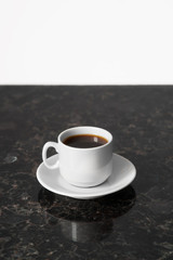 White cup of esoresso on granite table surface