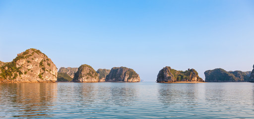 Landscape panorama of Ha Long Bay in north Vietnam. The bay consists of a dense cluster of some limestone monolithic islands each topped with thick jungle vegetation, rising from the ocean.