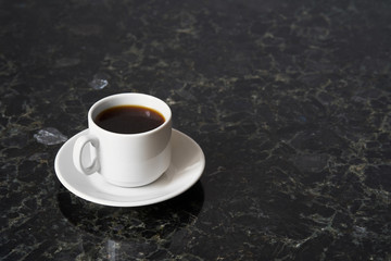 White cup of esoresso on granite table surface, copy space