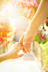 beautiful hands of a child and a parent in a park in nature