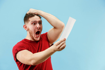 Young boy with a surprised happy expression bet slip on blue studio background. Human facial...