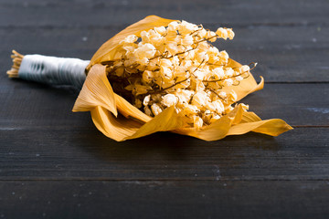 dried lily of the valley flowers on black wood table background