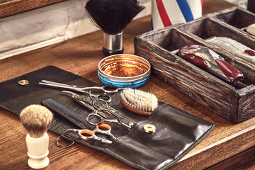 Hairdresser tools on wooden background. Top view on wooden table with scissors, comb, hairbrushes and hairclips, trimmer.