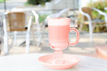 A cup of latte coral color on the table of the summer patio.