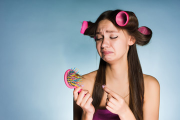 sad young girl loses her hair, on her hair curlers head