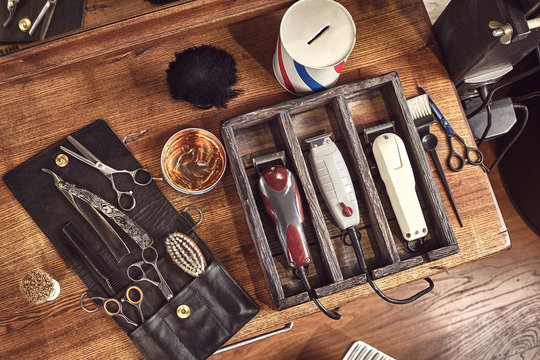 Hairdresser tools on wooden background. Top view on wooden table with scissors, comb, hairbrushes and hairclips, trimmer.