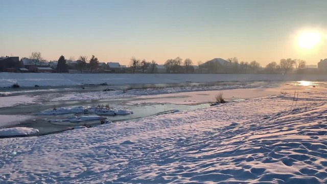 Frozen river covere by the snow. Sunset time. Winter