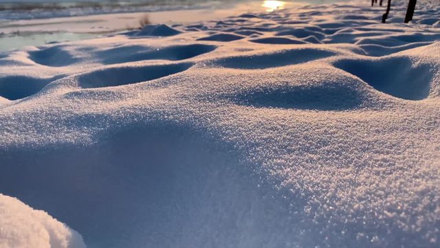 Snow slide. Close up view os snow. Nature. Sunset time. Frozen river in background