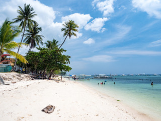 Beautiful tropical beach background from Alona Beach at Panglao Bohol island, the white sand beach with cloudy blue sky and palm trees. Travel Vacation, Philipines, november, 2018