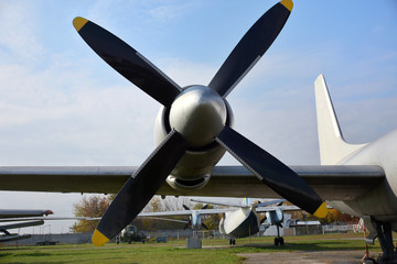Naklejka na ściany i meble Retro plane with propellers on blue sky background. Airplane details with clouds. Aviation transport on airfield. Black propeller blade with yellow on the top. Jet engine of an vintage airliner.