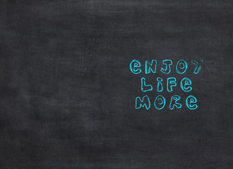 Enjoy Life More - text concept on blackboard from black background