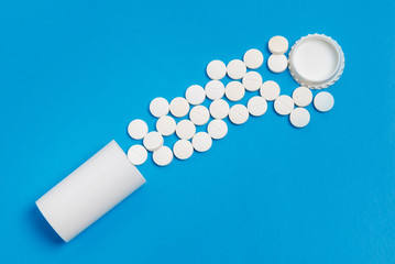 White tablets and bottle for tablets on blue background