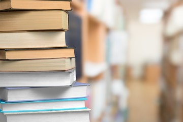 Collection of old books on wooden desk at library background
