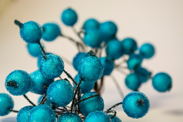 Texture. White background. Winter. An artificial branch of blue berries in hoarfrost. Dew drops. A decor for the house.