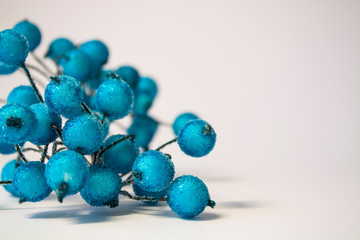 Texture. White background. Winter. An artificial branch of blue berries in hoarfrost. Dew drops. A decor for the house.