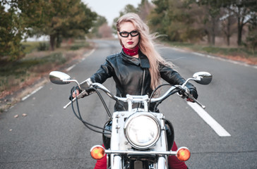 Fototapeta na wymiar Beautiful biker woman posing outdoor with motorcycle on the road. 