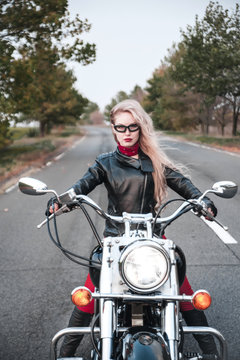 Beautiful biker woman posing outdoor with motorcycle on the road. © Alona
