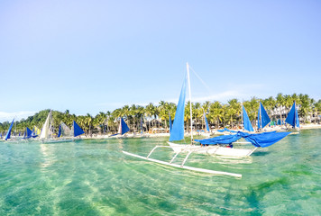 Small sailing boats for touristic excursions at sunset in Boracay island - Exclusive travel destination in Philippines - Vivid sunny filtered look