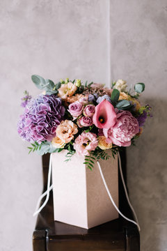 beautiful blossoming bouquet of fresh hydrangea, calla lilies, roses, eustoma, carnations, eucalyptus, mattiola flowers in purple color on the grey wall background 
